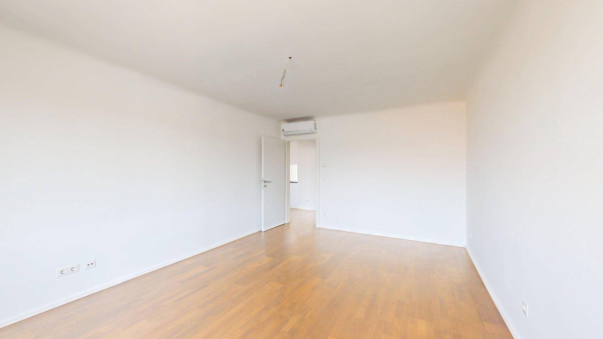 Geräumiges Schlafzimmer mit Holzboden und Klimaanlage, ideal für erholsame Nächte.