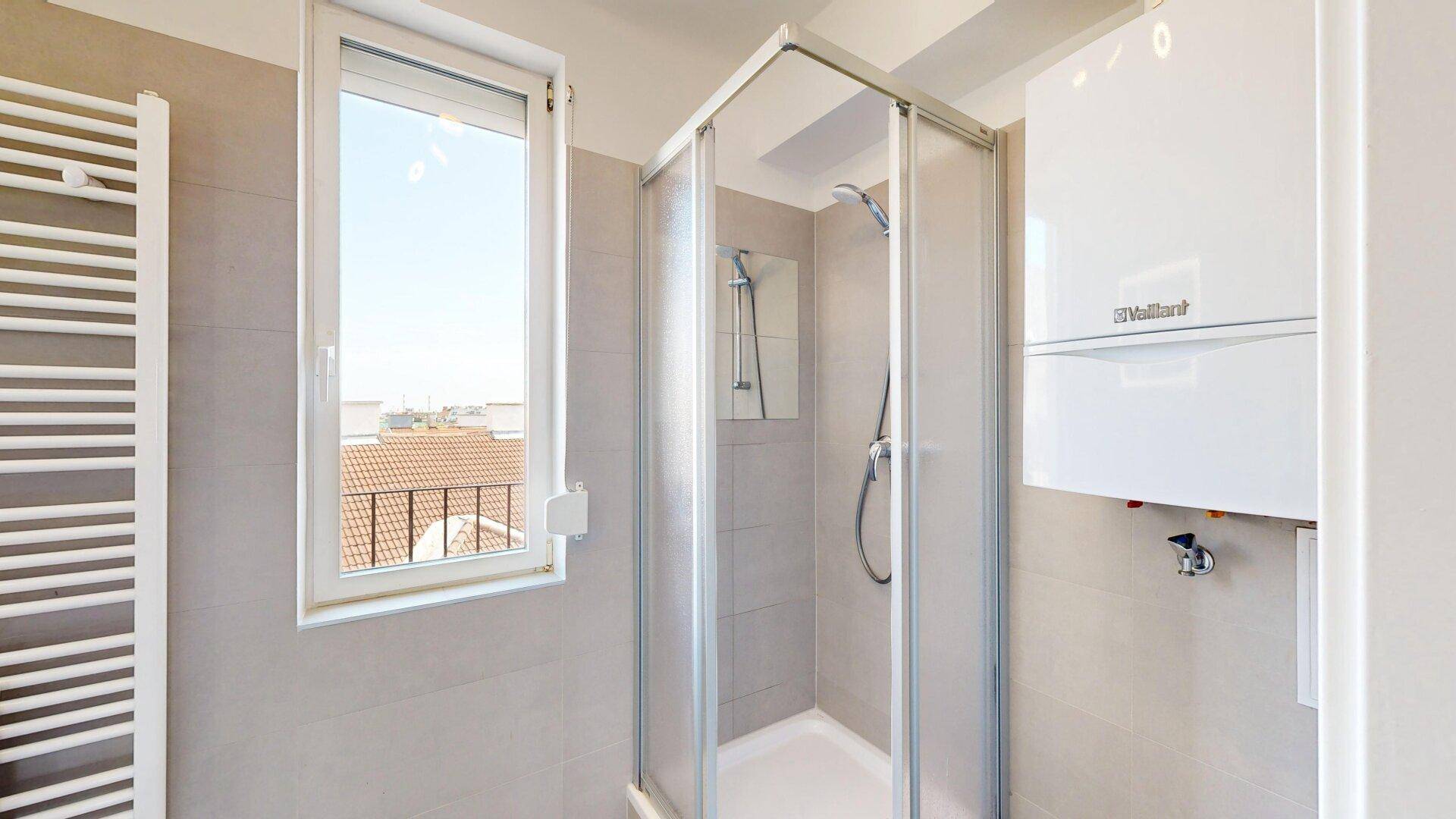 Helles Badezimmer mit Duschkabine, Fenster und einem modernen Warmwasserbereiter.