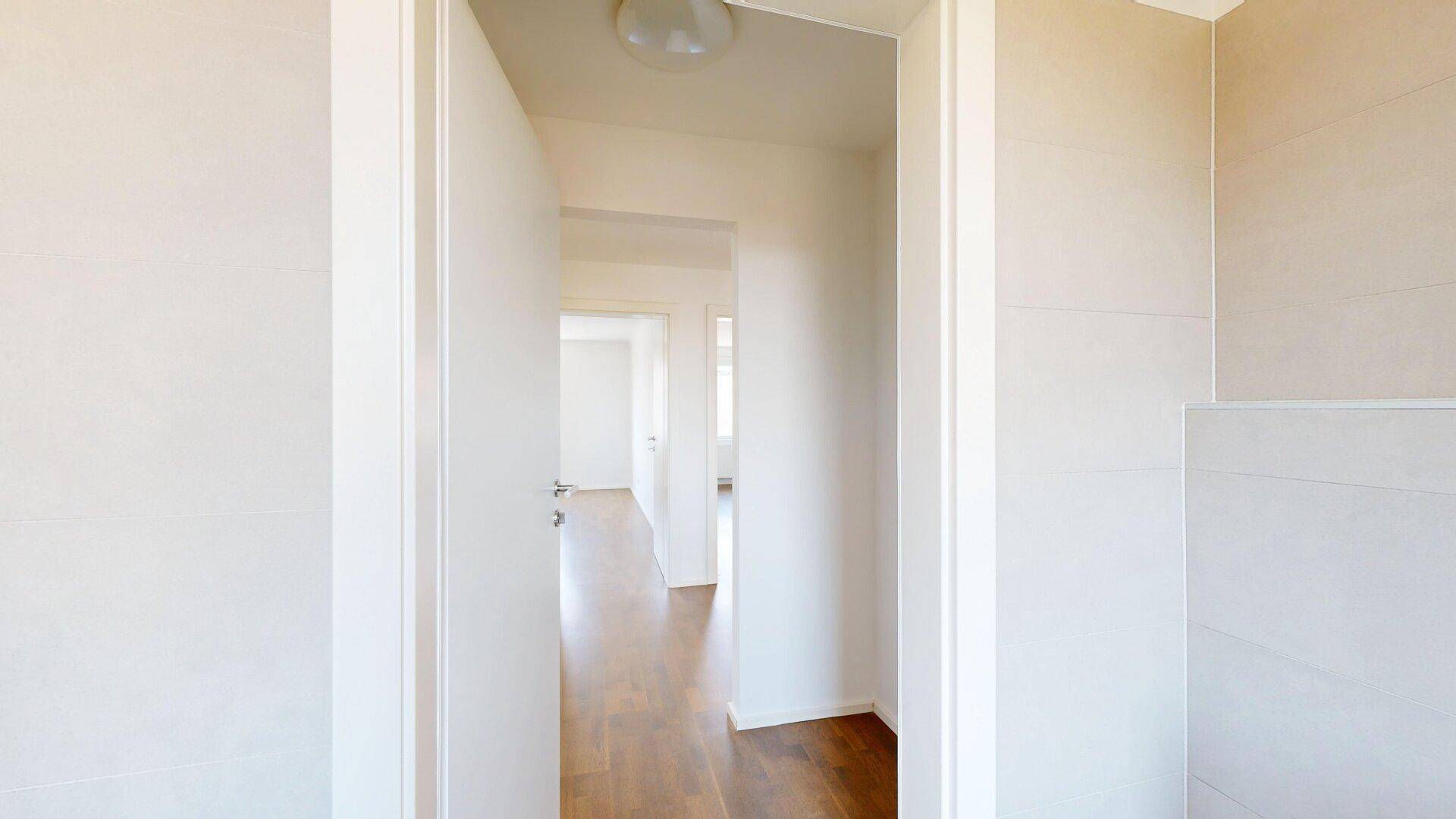 Langer, heller Flur mit Holzboden, der zu verschiedenen Zimmern der Wohnung führt.
