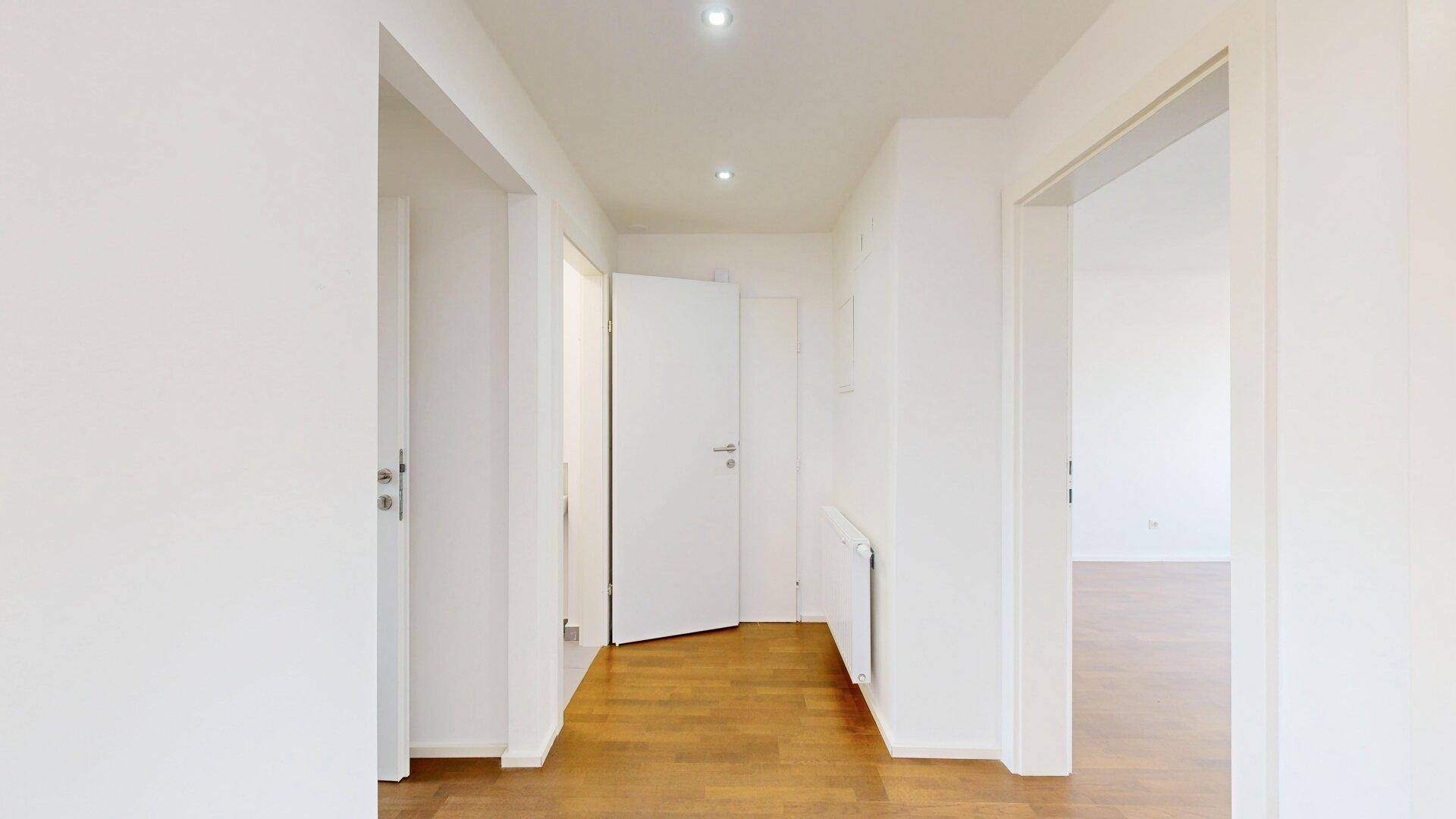 Geräumiger Flur mit Holzboden und Zugang zu mehreren Zimmern der Wohnung.