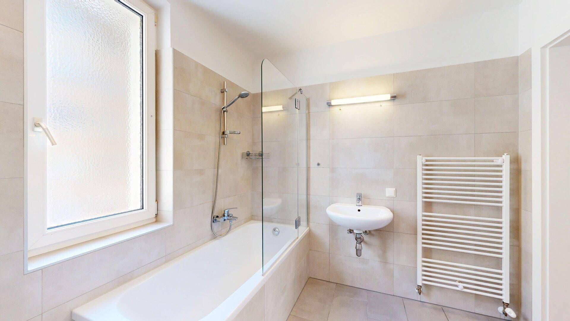 Modernes Badezimmer mit Badewanne, Duschabtrennung und beheiztem Handtuchhalter.