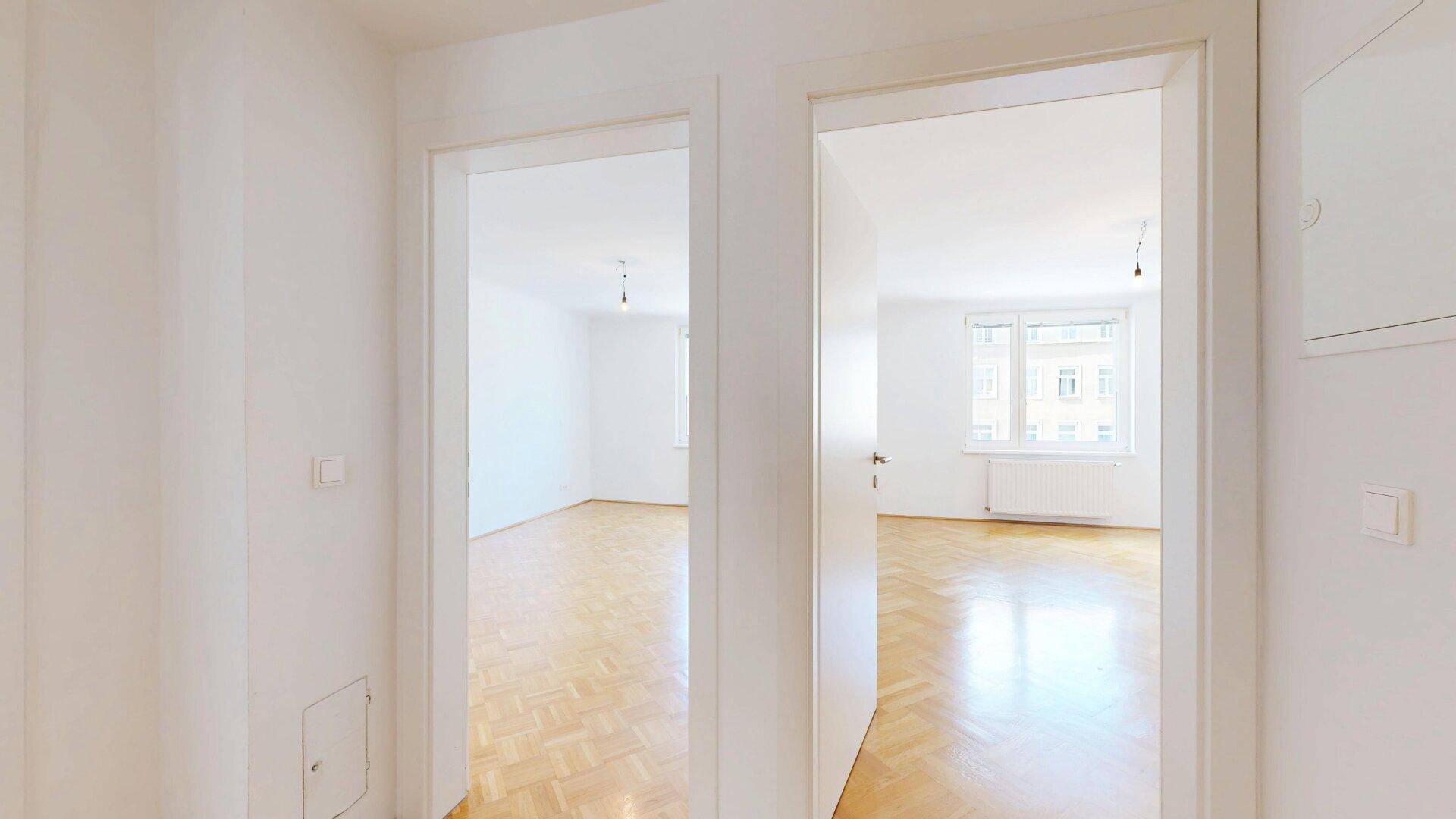 Heller Flur mit Holzboden, der den Zugang zu zwei weiteren Zimmern ermöglicht.