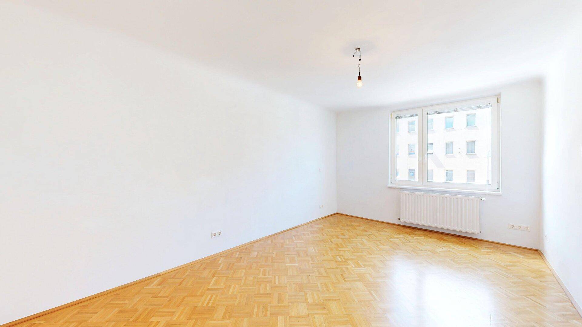 Helles Schlafzimmer mit klassischem Fischgrätparkett und einem Fenster mit Blick nach draußen.