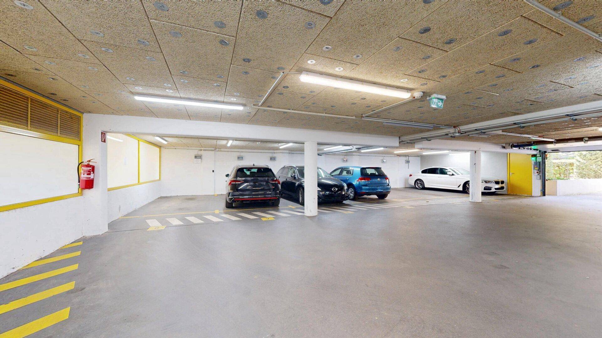 Tiefgarage mit mehreren Stellplätzen und heller Beleuchtung.