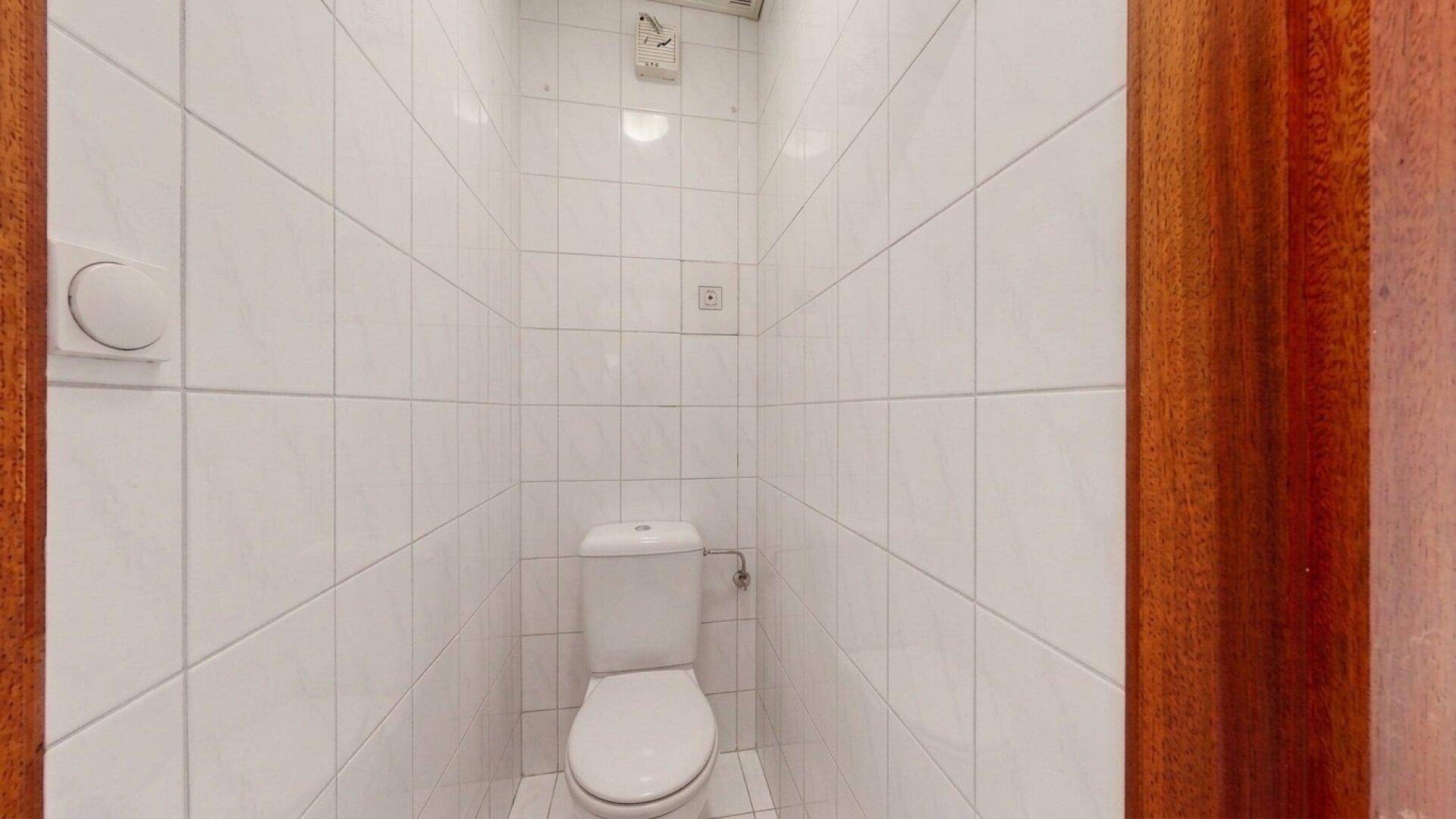 Kleines Gäste-WC mit weißen Fliesen an Wänden und Boden.