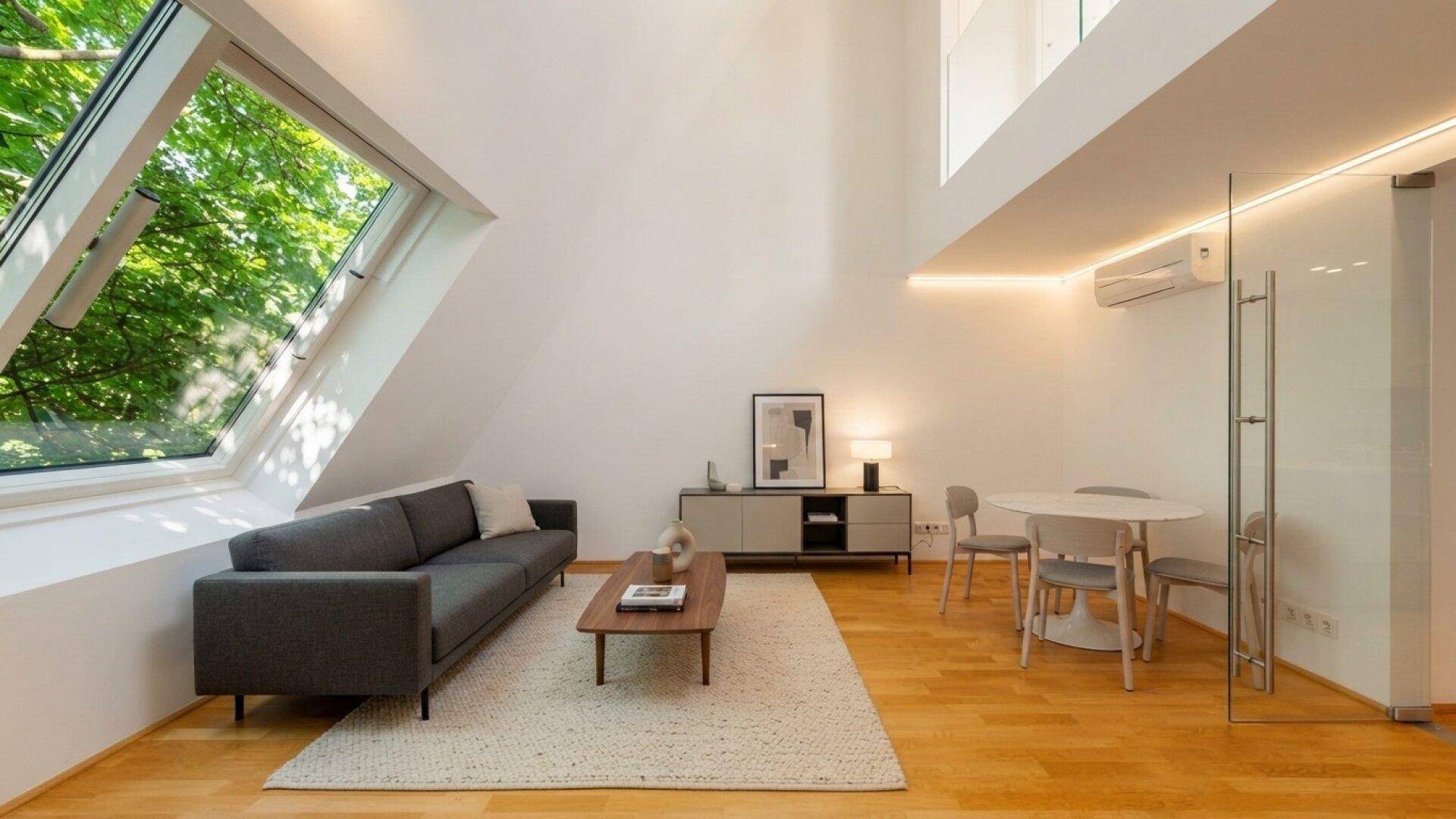 Helles Wohnzimmer mit modernem Sofa, Holzboden und großem Dachfenster mit Blick ins Grüne.