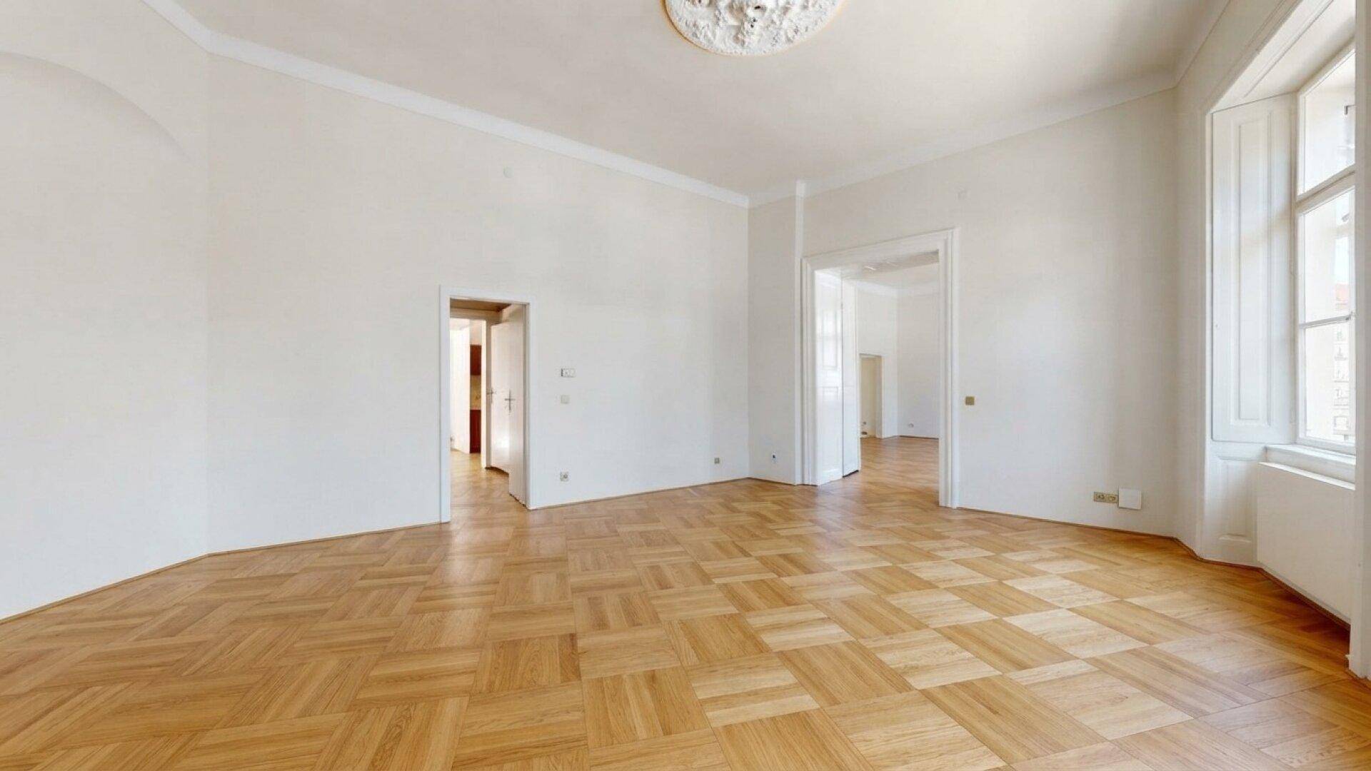 Klassischer Raum mit quadratischem Parkettboden, hohen Decken und einem verzierten Deckenmedaillon.