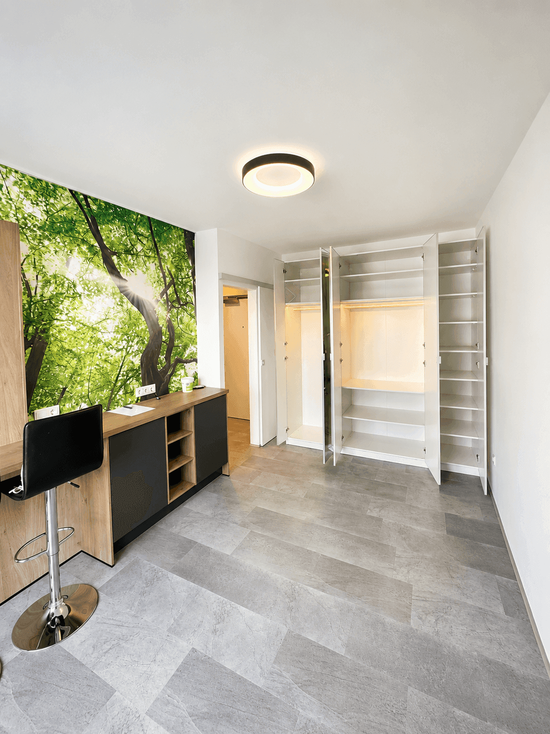 Heller Wohnraum mit offenem Kleiderschrank, moderner Deckenleuchte und Natur-Wandtapete.