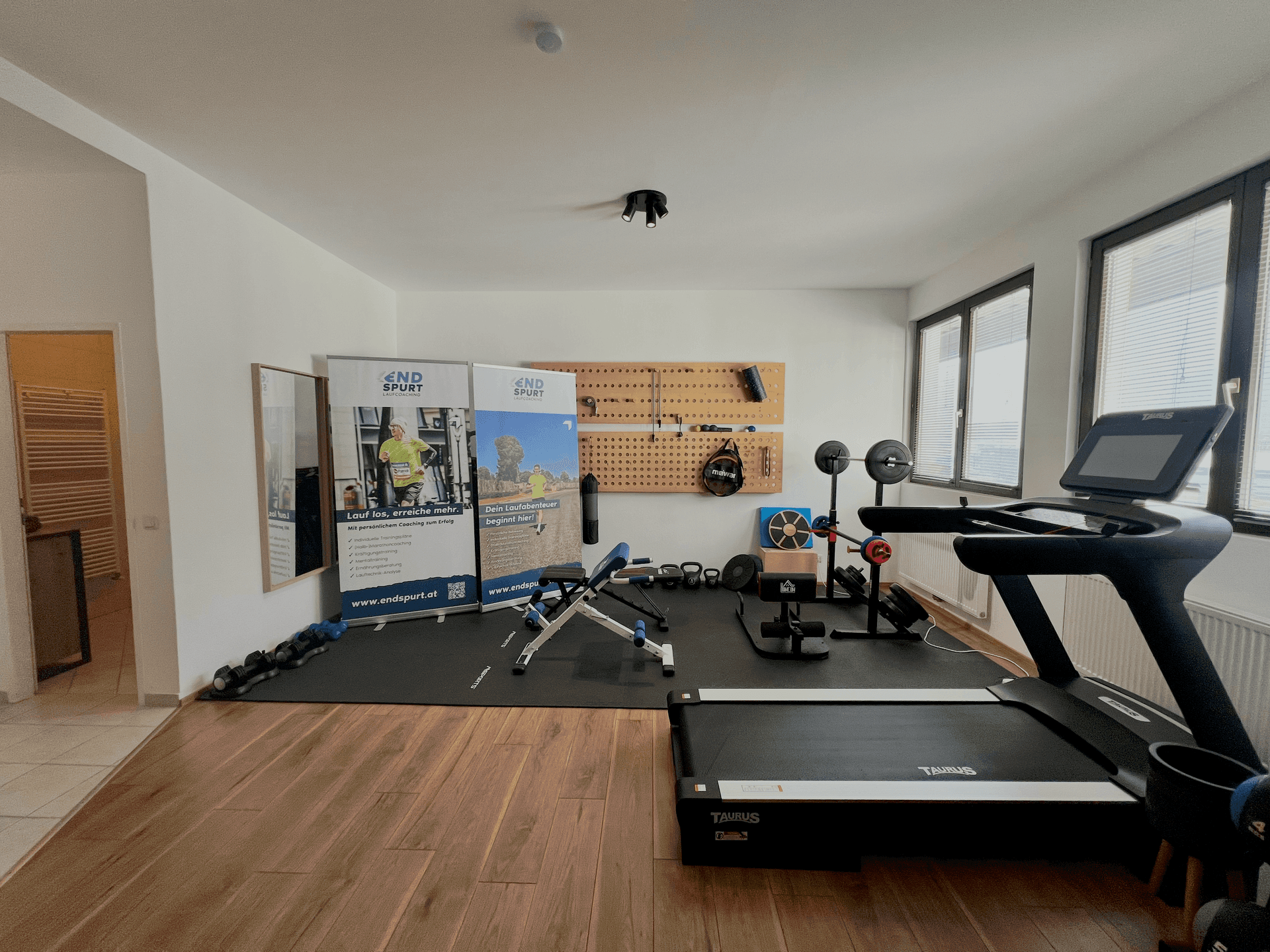 Geräumiger Fitnessbereich mit Laufband, Hanteln und Trainingsbank, ideal für das Heimtraining.