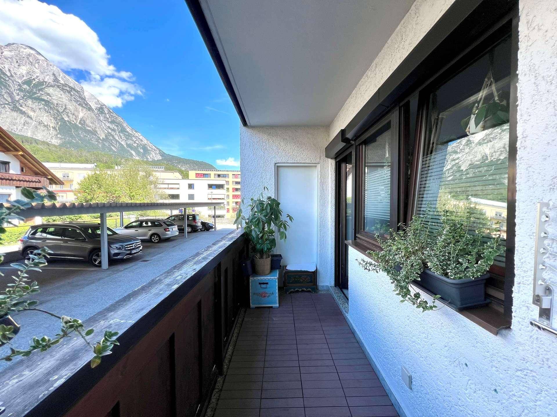 Schmaler Balkon mit Bergblick und Blick auf den Parkplatz, ausgestattet mit Pflanzen.