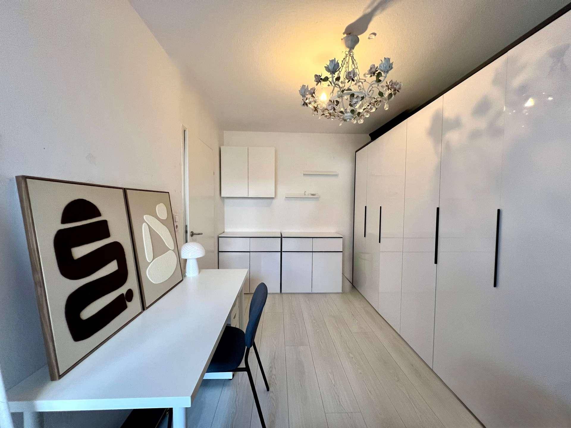 Helles Schlafzimmer mit großen weißen Einbauschränken, Schreibtisch und modernem Dekor.