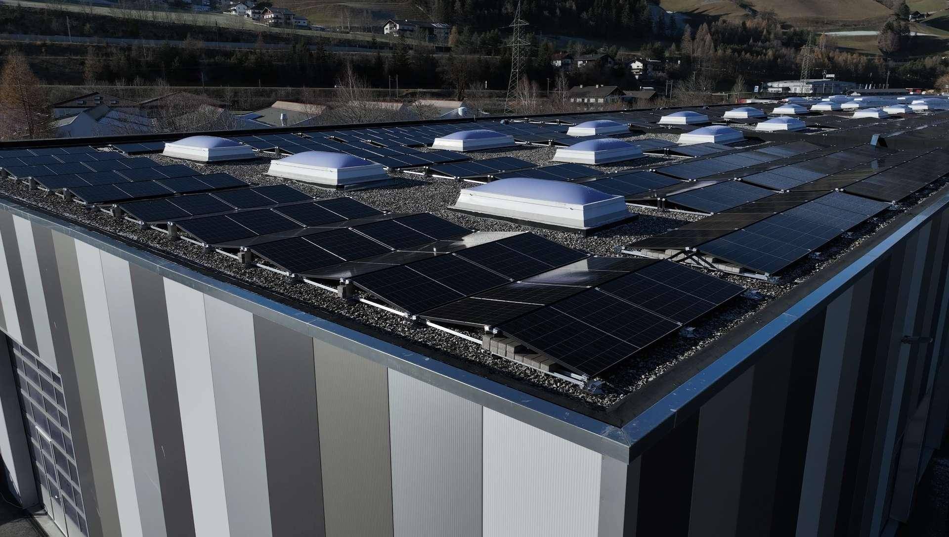 Dach eines modernen Gewerbegebäudes mit zahlreichen Photovoltaik-Modulen und Oberlichtern.