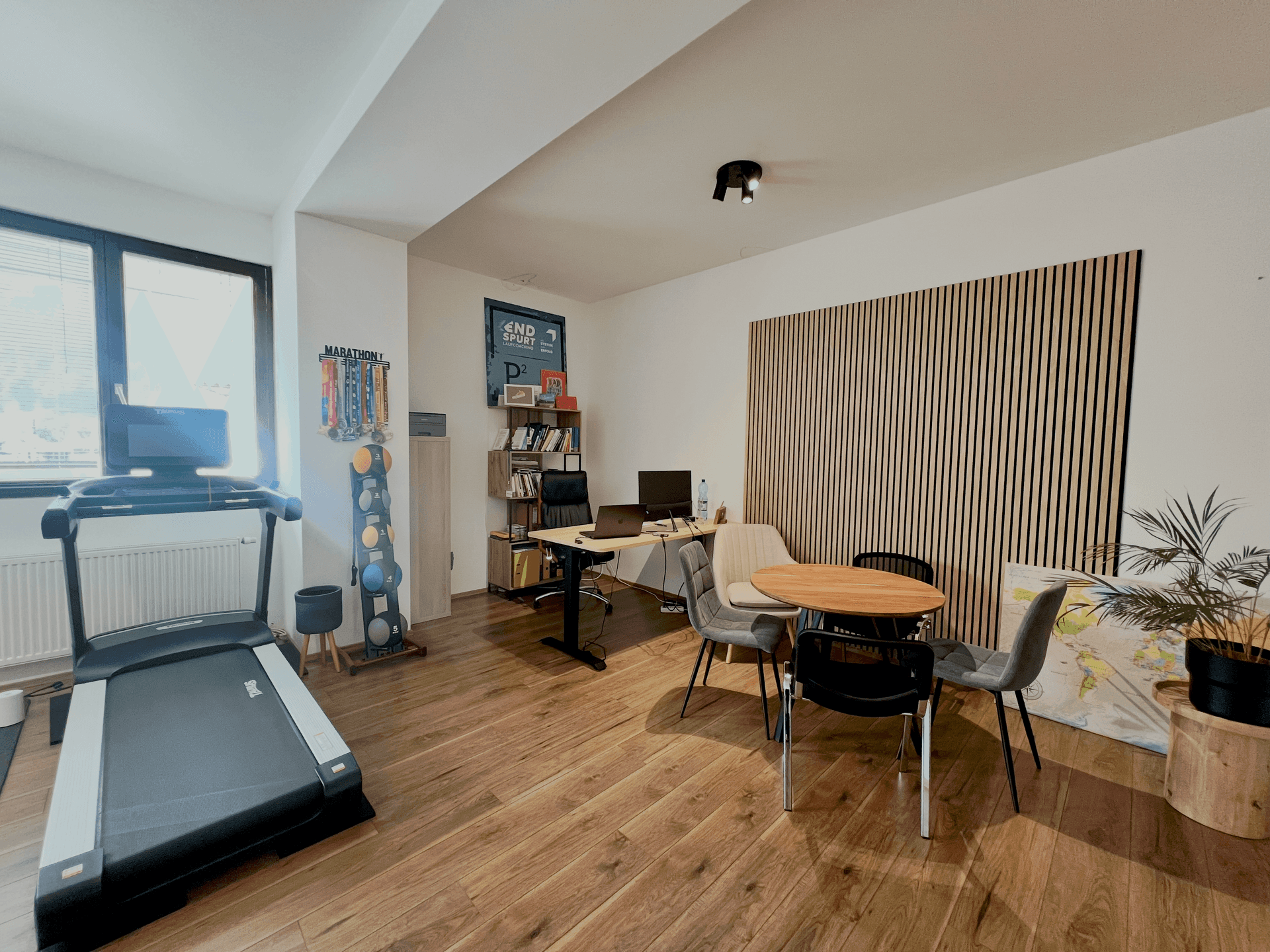 Moderner Bürobereich mit Schreibtischen, Besprechungstisch und dekorativer Holzlamellenwand.