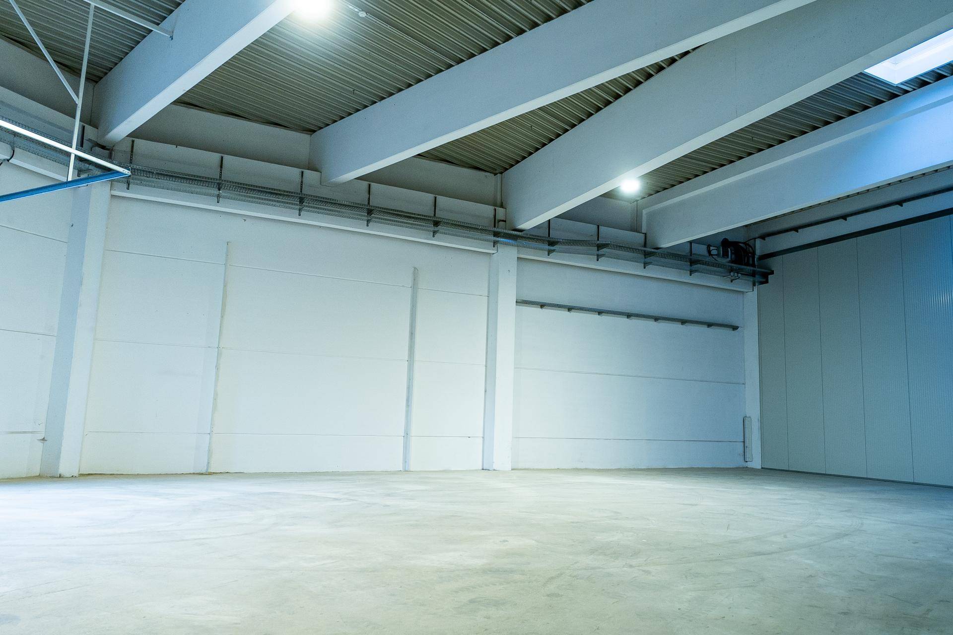 Weitläufiger Innenraum einer modernen Lagerhalle mit hohen Decken, Betonboden und sauberer Wandgestaltung.
