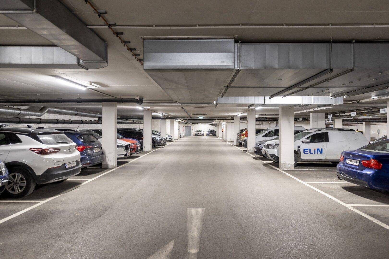 Geräumige Tiefgarage mit vielen geparkten Autos und klar markierten Stellplätzen.