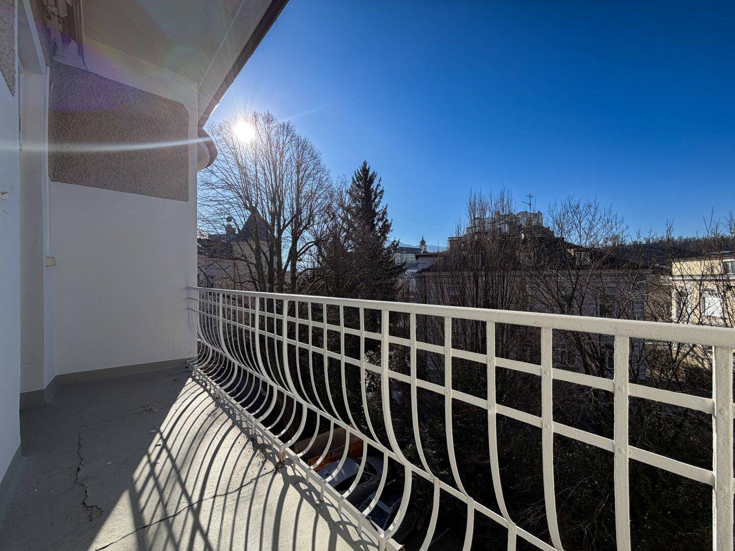 Sonniger Balkon mit schmiedeeisernem Geländer und Blick auf die Stadt und die Festung.