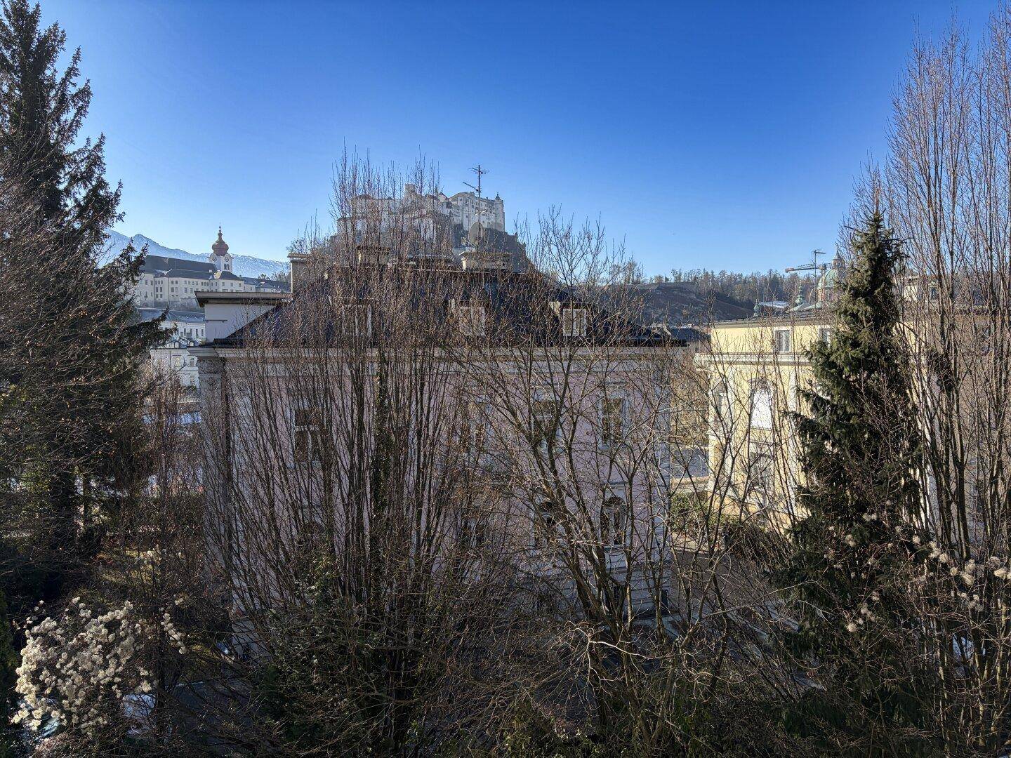 Panoramablick auf die Stadt mit historischen Gebäuden und der Festung Hohensalzburg im Hintergrund.