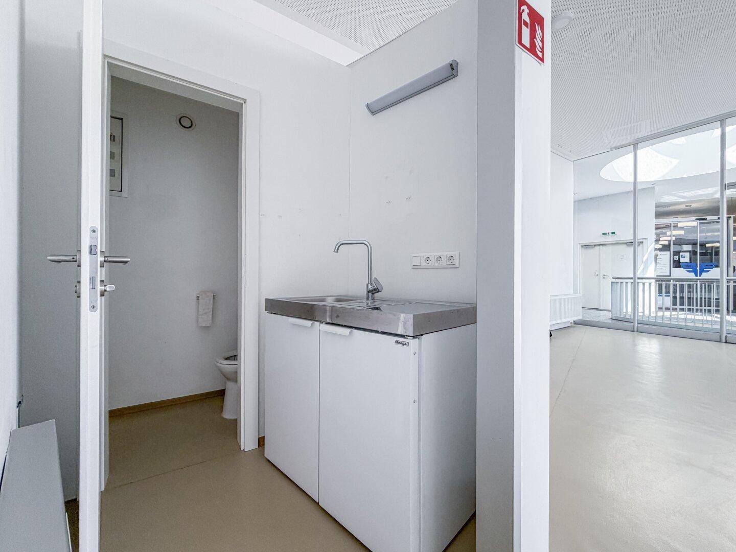 Kleiner Hauswirtschaftsraum mit Waschbecken und Zugang zu einer Toilette, praktisch und funktional.