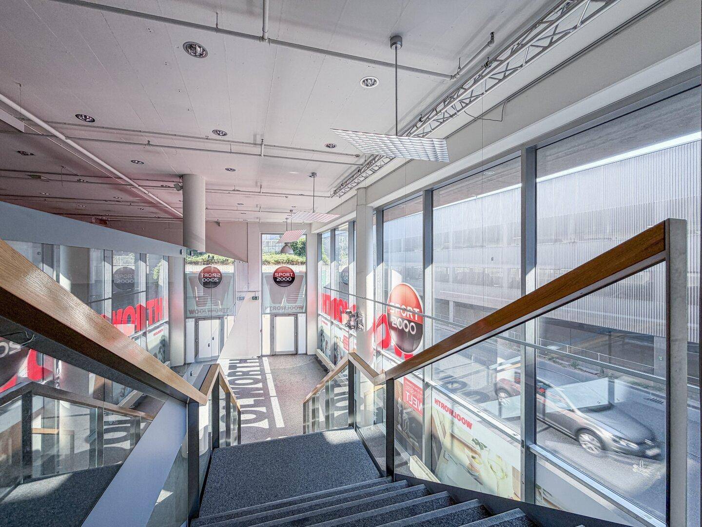 Blick von der Galerie auf die Treppe und die großen Fensterfronten des Gewerbeobjekts.