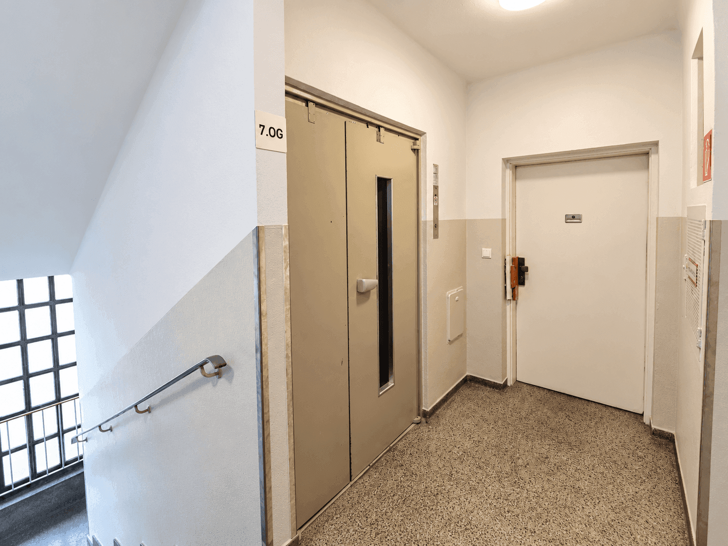 Treppenhaus mit Aufzugstür und einem Schild, das die 7. Etage anzeigt.