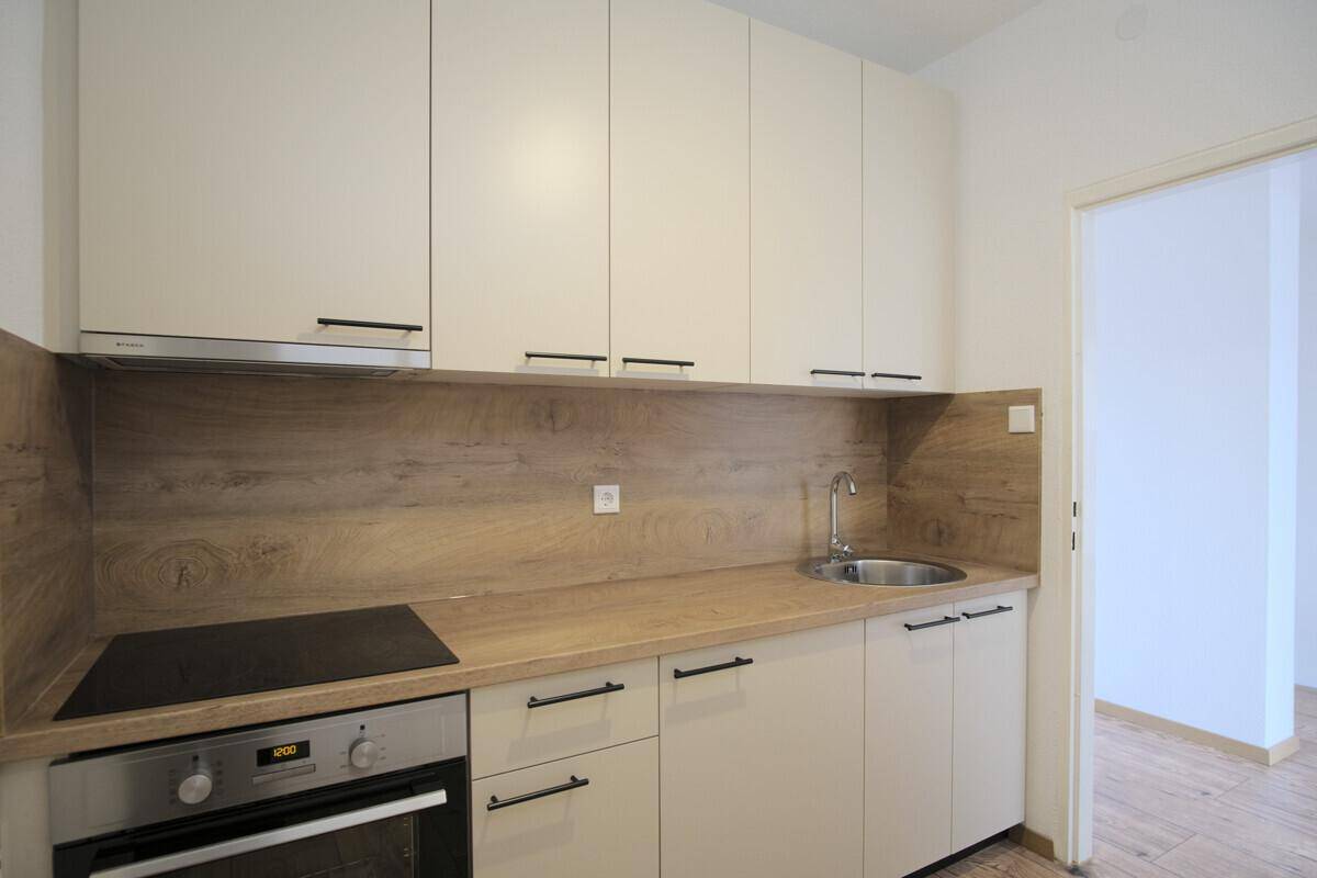 Kompakte Einbauküche mit zeitgemäßem Design, Kochfeld und Spüle, ideal für kleine Wohnungen.