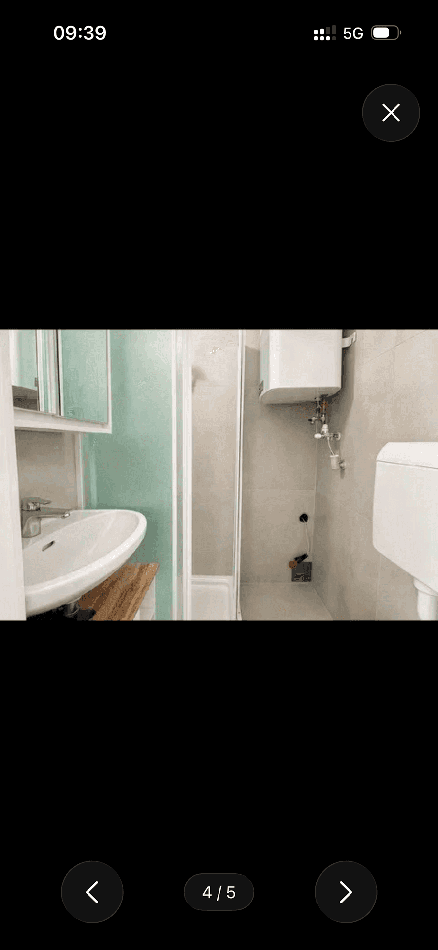 Modernes Badezimmer mit Duschkabine, Waschbecken, Toilette und Warmwasserboiler an der Wand.