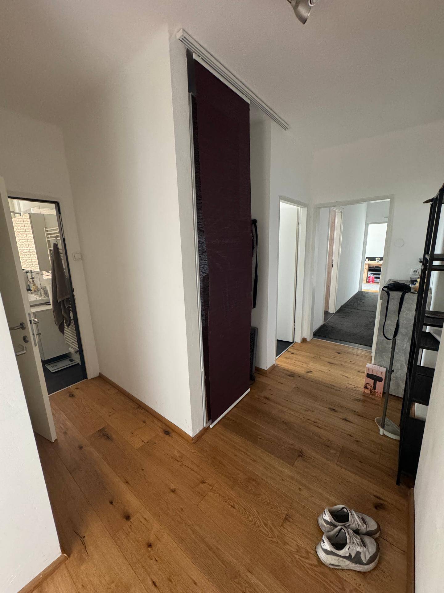 Heller Flur mit Holzfußboden, der zu verschiedenen Räumen führt.