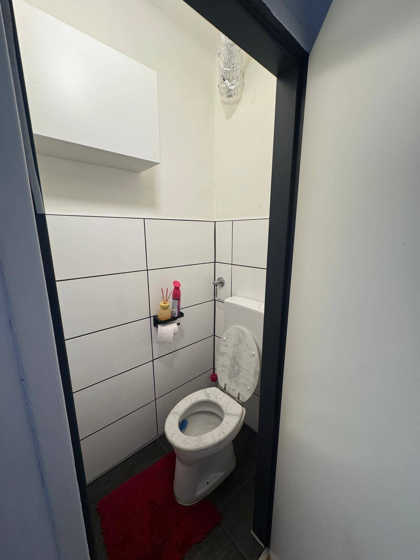 Kleines Gäste-WC mit Wandfliesen und einfacher Ausstattung.