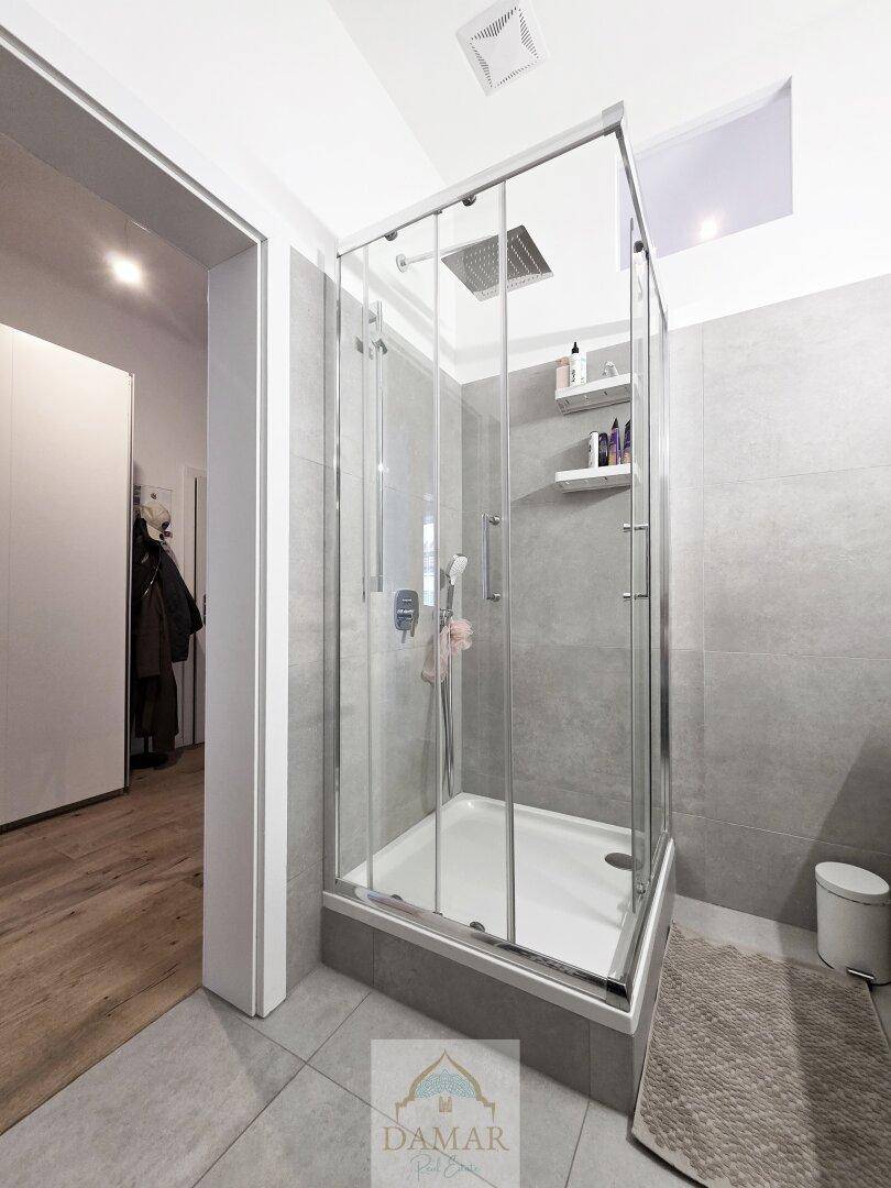 Duschkabine mit Glaswänden und modernen grauen Fliesen im Badezimmer, bietet eine praktische Duschlösung.