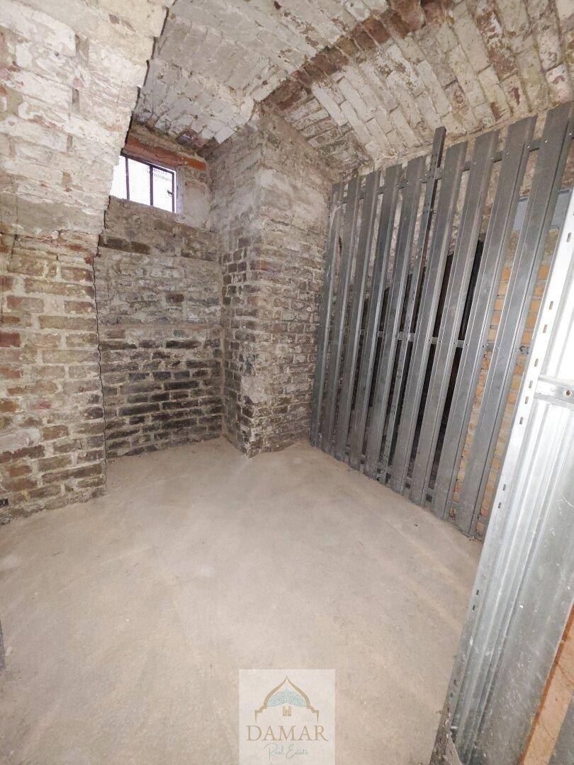 Rustikaler Kellerraum mit unverputzten Ziegelwänden und kleinem Fenster, bietet zusätzlichen Stauraum.