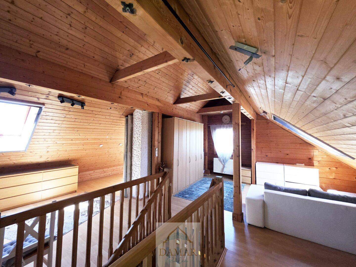 Offener Dachbodenbereich mit Einbauschränken, Holzbalken und Dachfenstern.