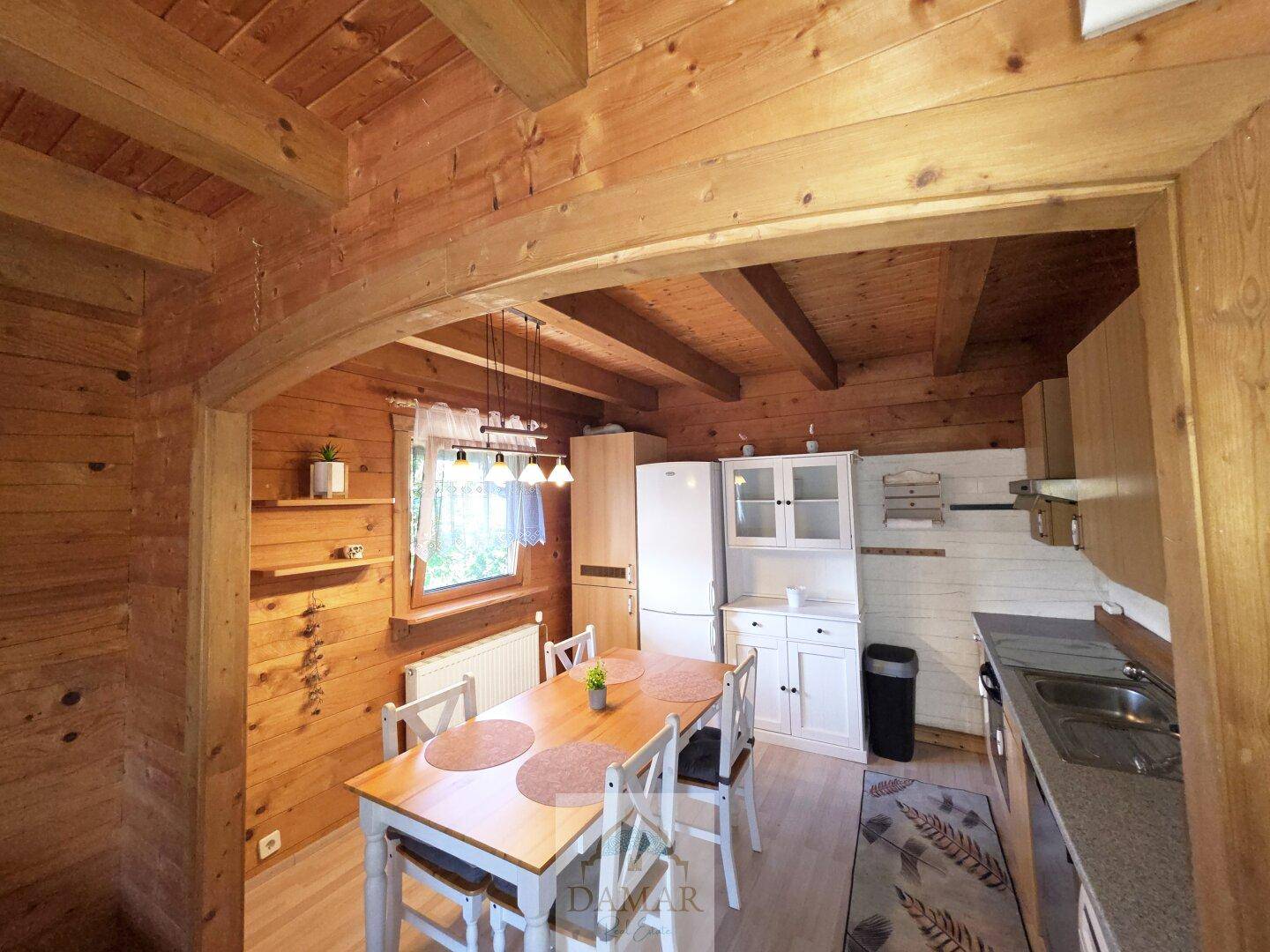 Helle Wohnküche mit Esstisch, weißen Schränken und viel Holz im Landhausstil.