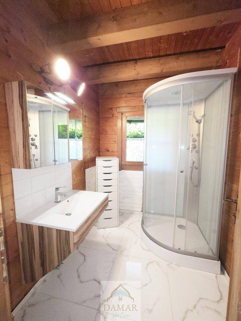 Modernes Badezimmer mit Duschkabine, Waschtisch und weißen Fliesen.