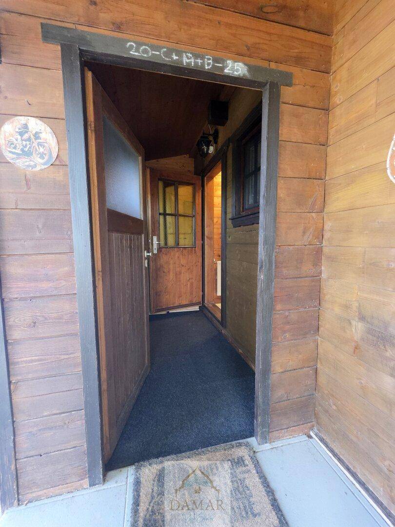 Offene Eingangstür mit Blick in den Flur und die Holzvertäfelung des Hauses.