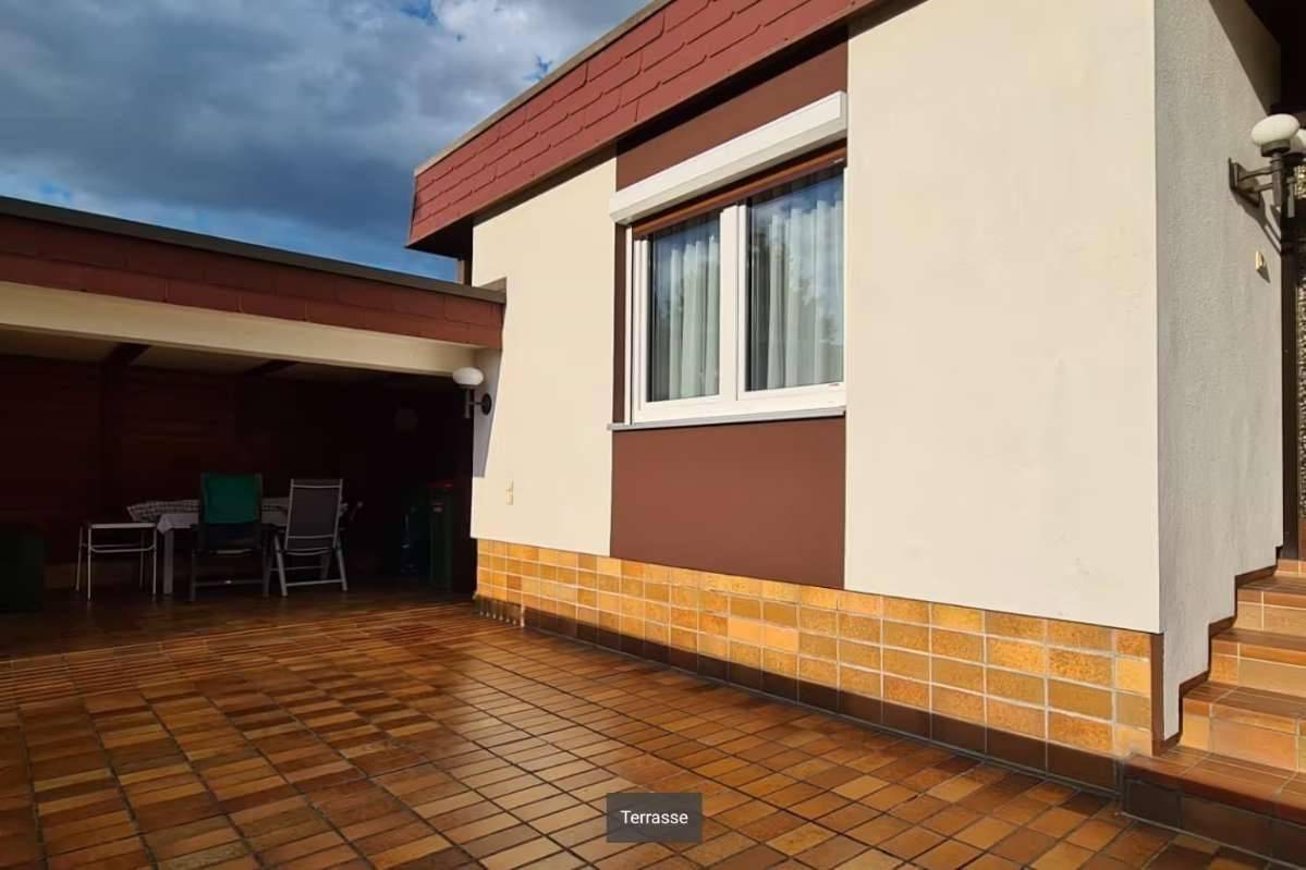 Gedeckte Terrasse mit Fliesenboden und Sitzgelegenheiten, ideal für entspannte Stunden im Freien.