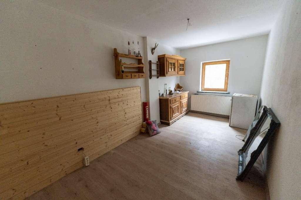 Unmöblierter Raum mit Holzfußboden, Fenster und rustikalen Wanddekorationen, bereit zur Gestaltung.