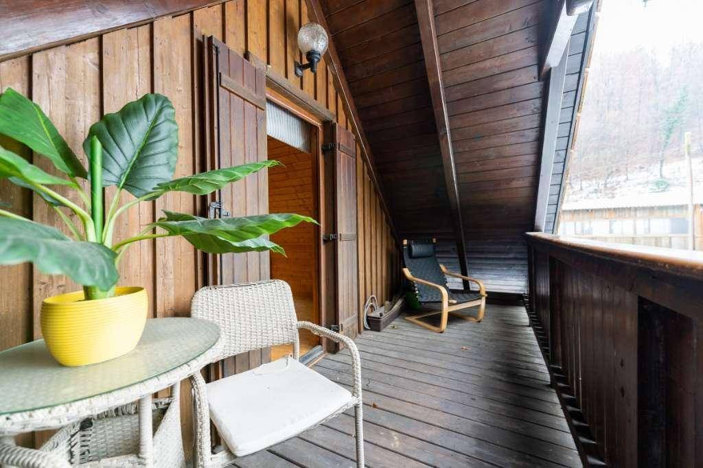 Überdachter Holzbalkon mit Sitzgelegenheiten und einem schönen Blick ins Grüne.