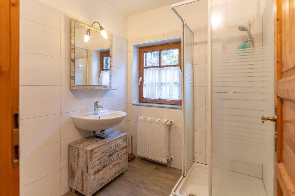 Helles Badezimmer mit Duschkabine, modernem Waschbecken und einem Fenster für Tageslicht.