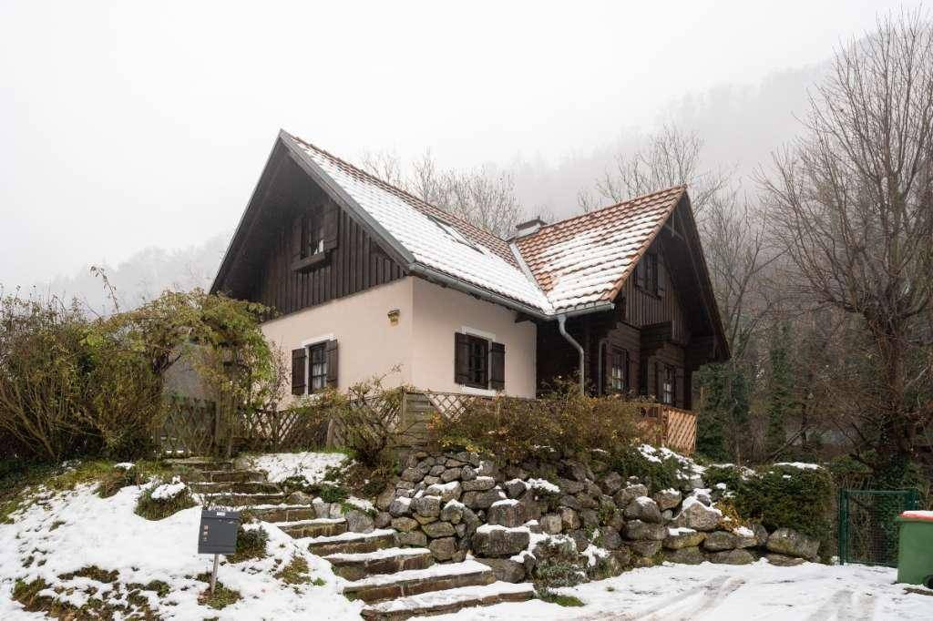 Traditionelles Haus mit Holzelementen und Ziegeldach, umgeben von Schnee und Bäumen im Winter.