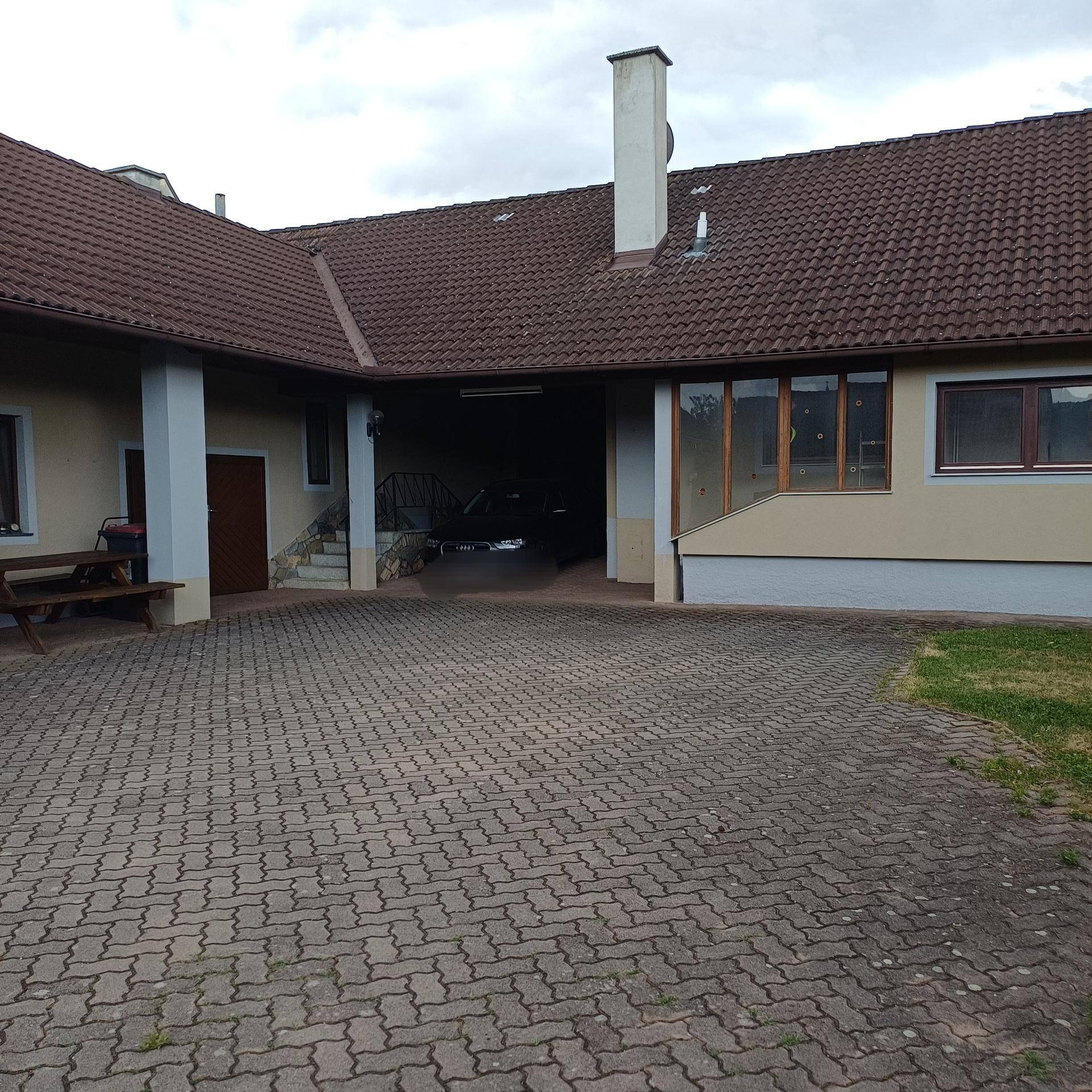 Gebäudeaußenansicht mit gepflastertem Hof und überdachtem Zugangsbereich.