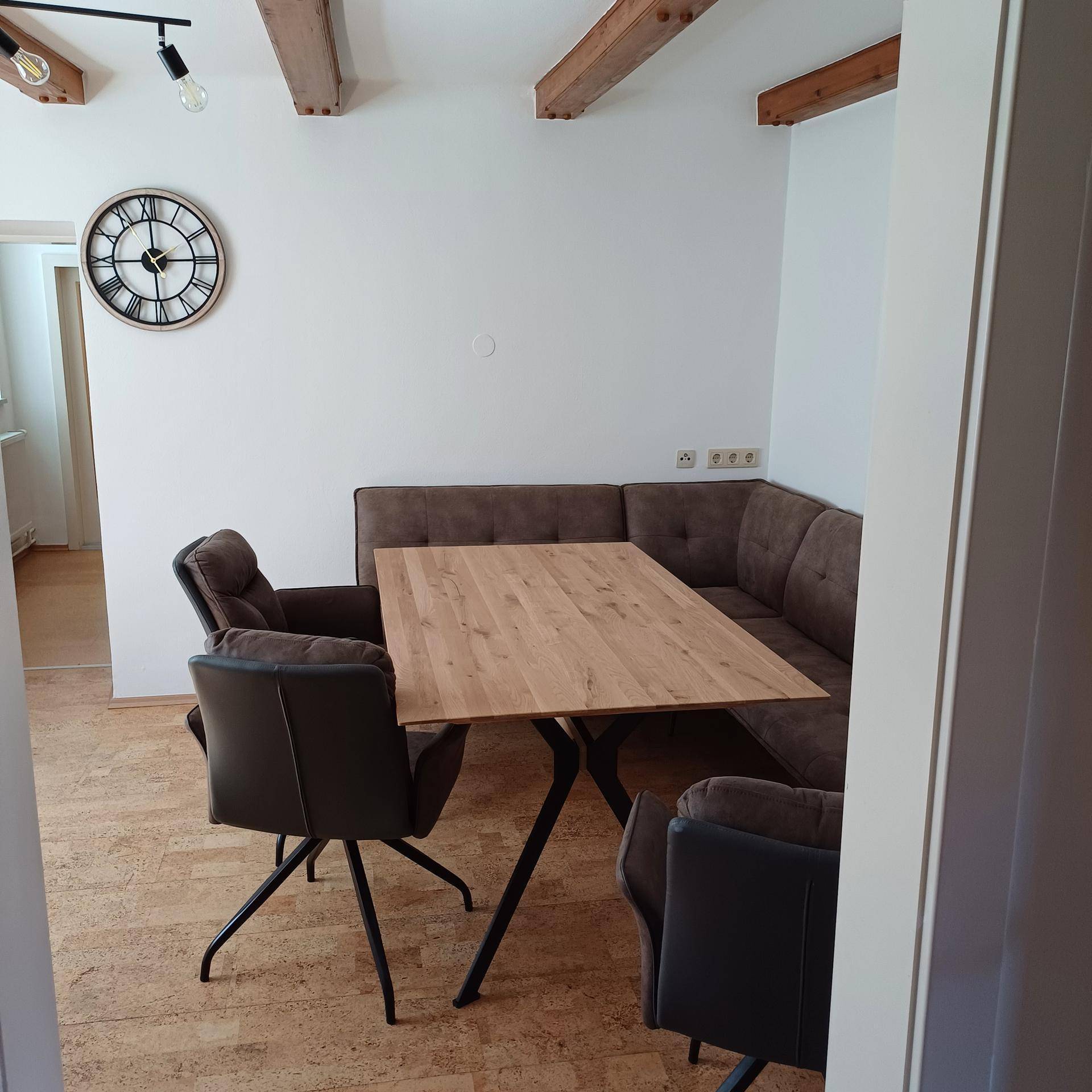Gemütlicher Essbereich mit Holztisch, Eckbank und freiliegenden Holzbalken an der Decke.