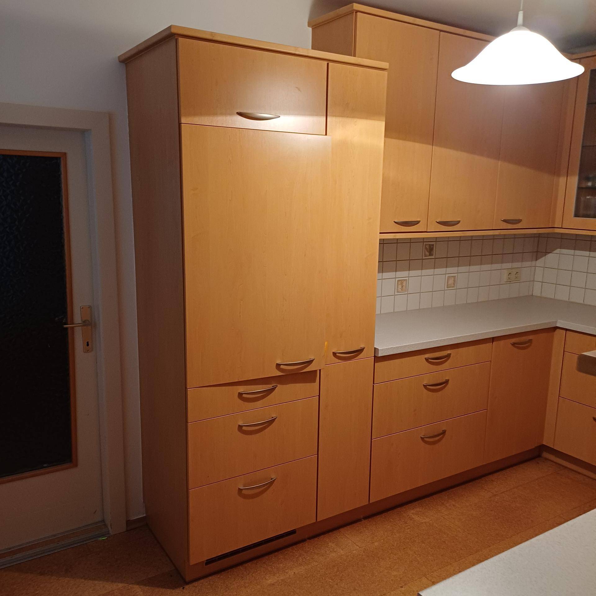 Küche mit hellen Holzschränken, weißer Arbeitsplatte und praktischem Stauraum.