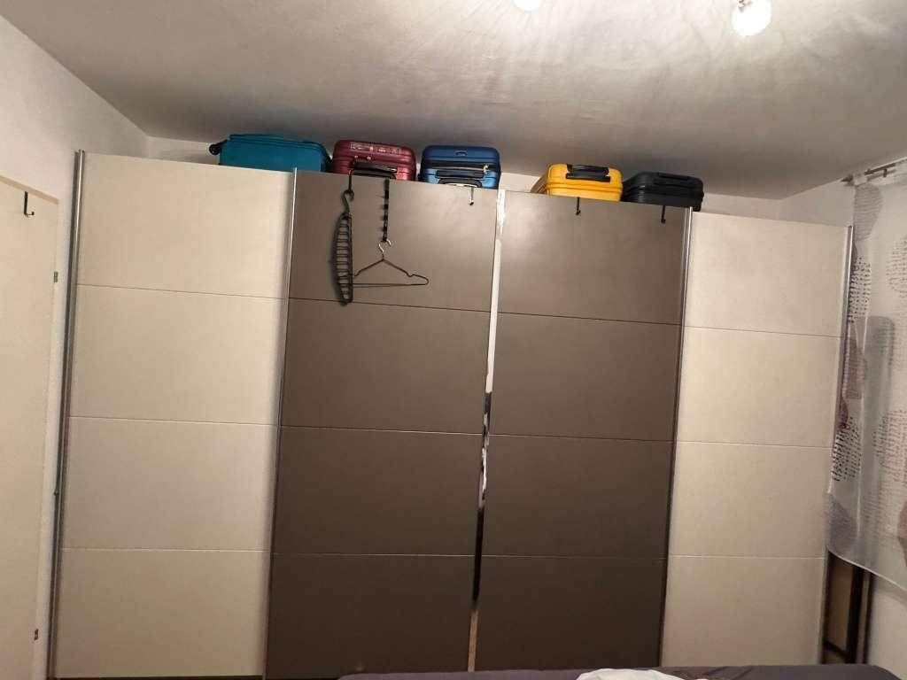 Großer Einbauschrank mit Schiebetüren und Stauraum für Gepäck im Schlafzimmer.