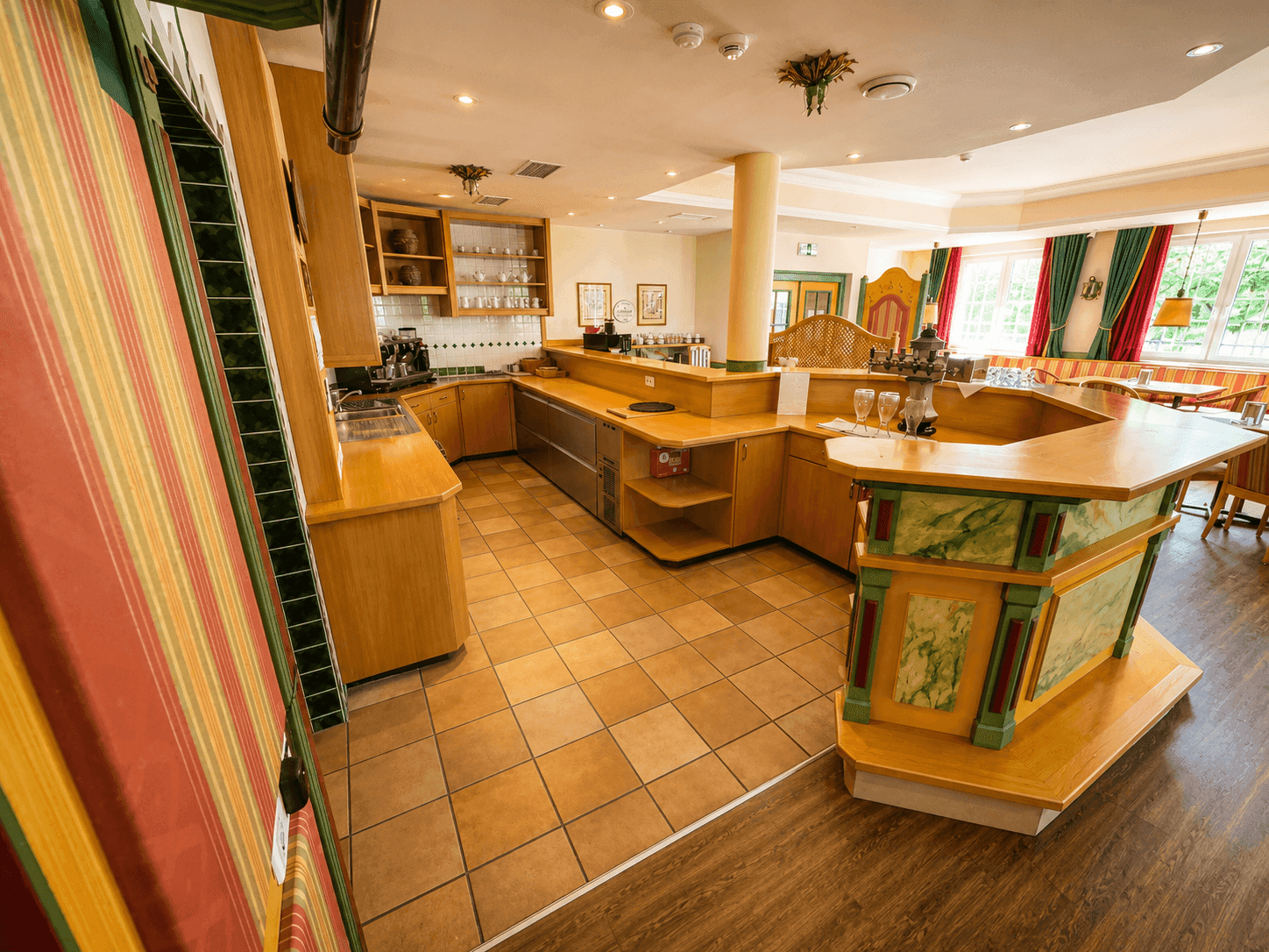 Professionelle Küche mit gefliestem Boden, Holzarbeitsplatten und integrierten Geräten für den Restaurantbetrieb.