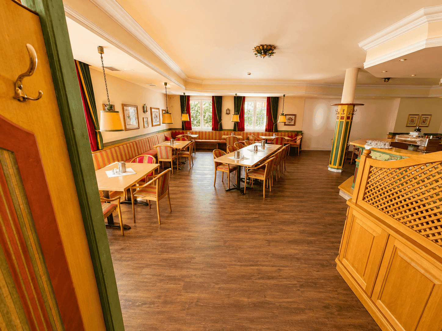 Weitläufiger Speisesaal mit Holzboden, traditionellen Möbeln und großen Fenstern für natürliche Beleuchtung.