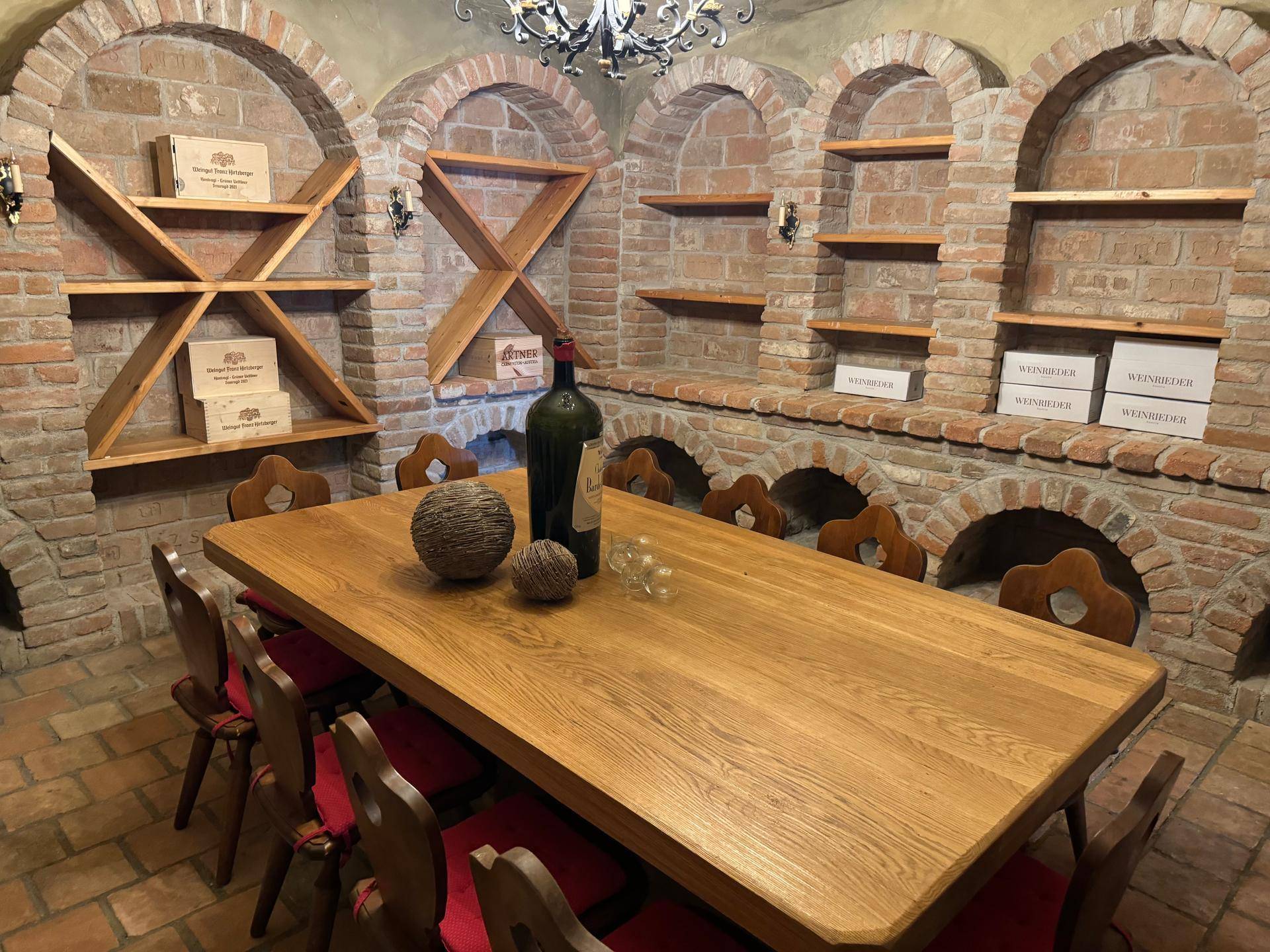 Gemütlicher Weinkeller mit massivem Holztisch, Ziegelwänden und Regalen für eine umfangreiche Weinsammlung.