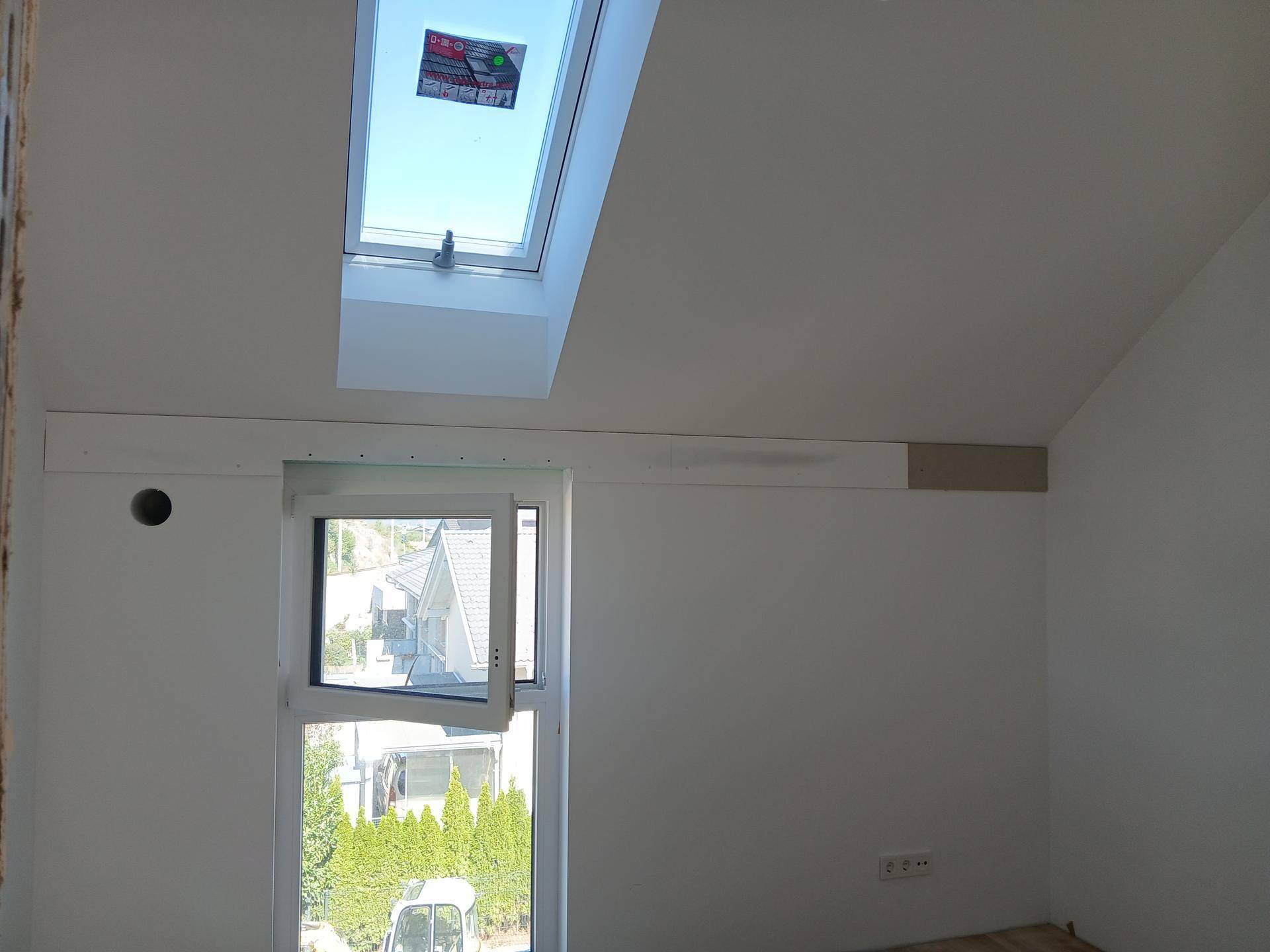 Dachgeschosszimmer mit Holzboden, Dachschräge und einem geöffneten Dachfenster.