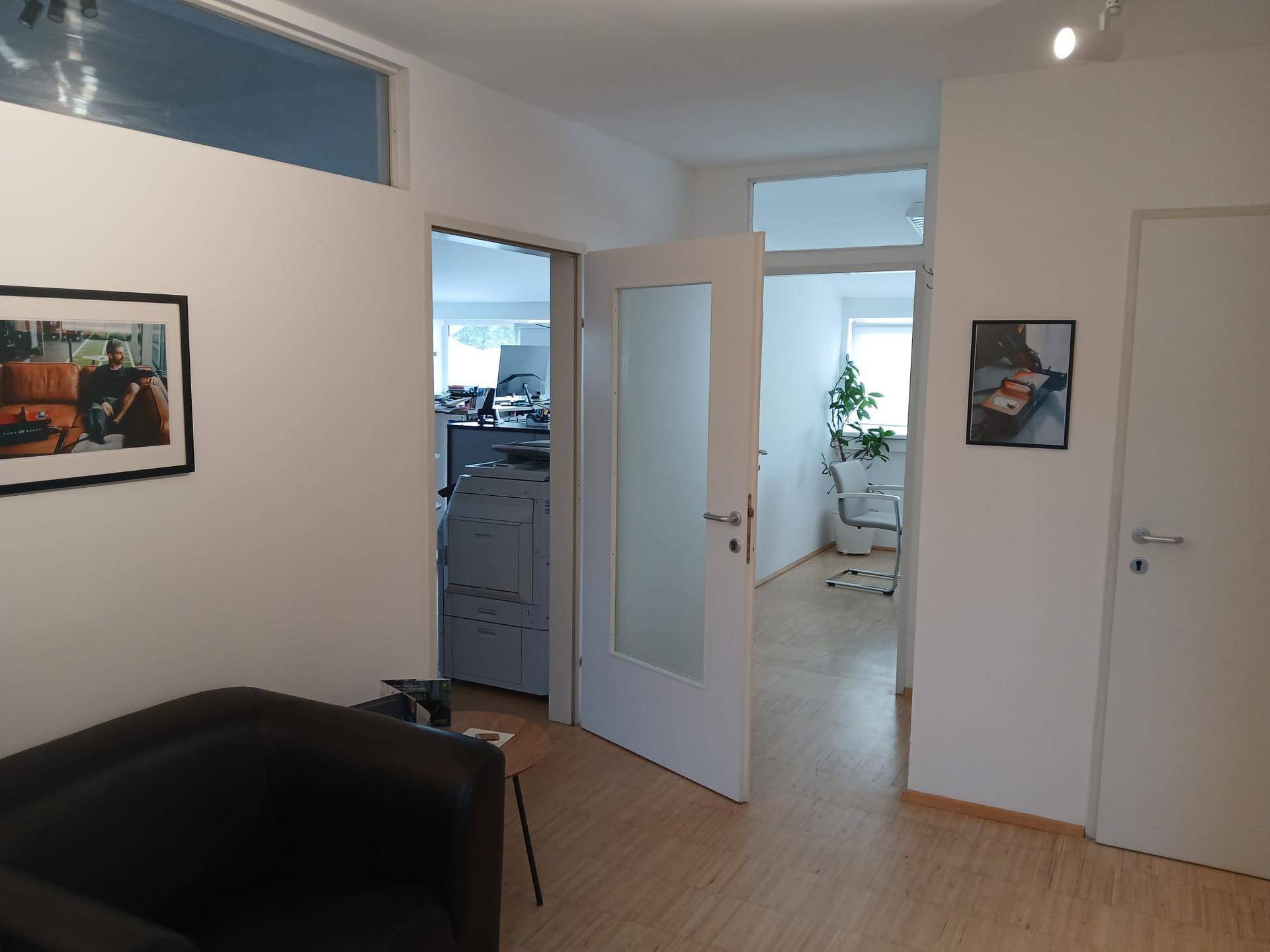 Flur mit Türen zu weiteren Räumen, einer kleinen Sitzecke und Bildern an den Wänden.