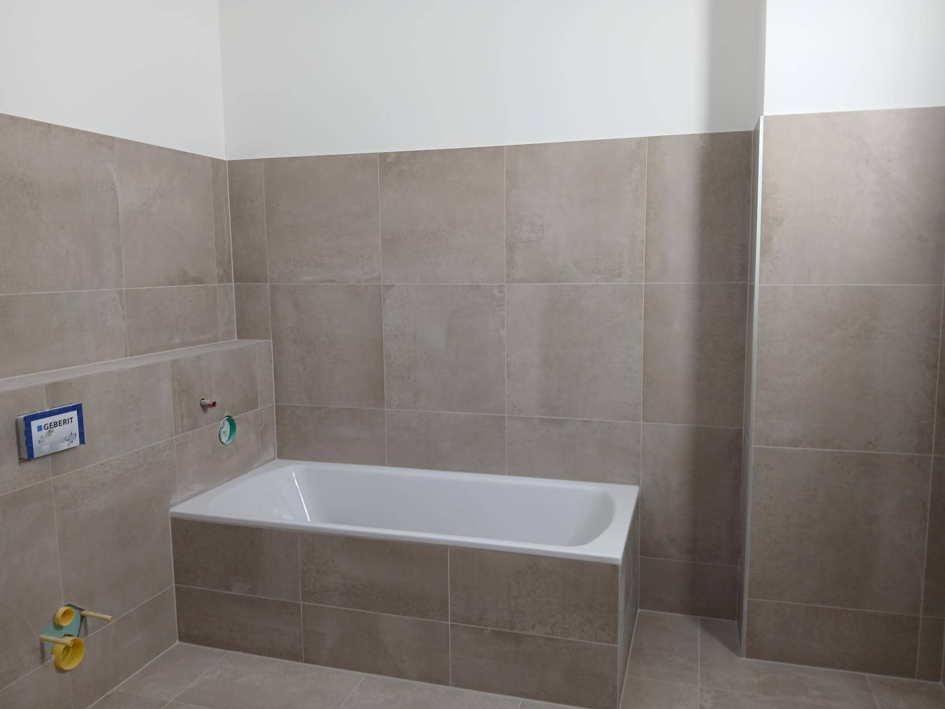 Modern gefliestes Badezimmer mit eingebauter Badewanne, noch im Bau.