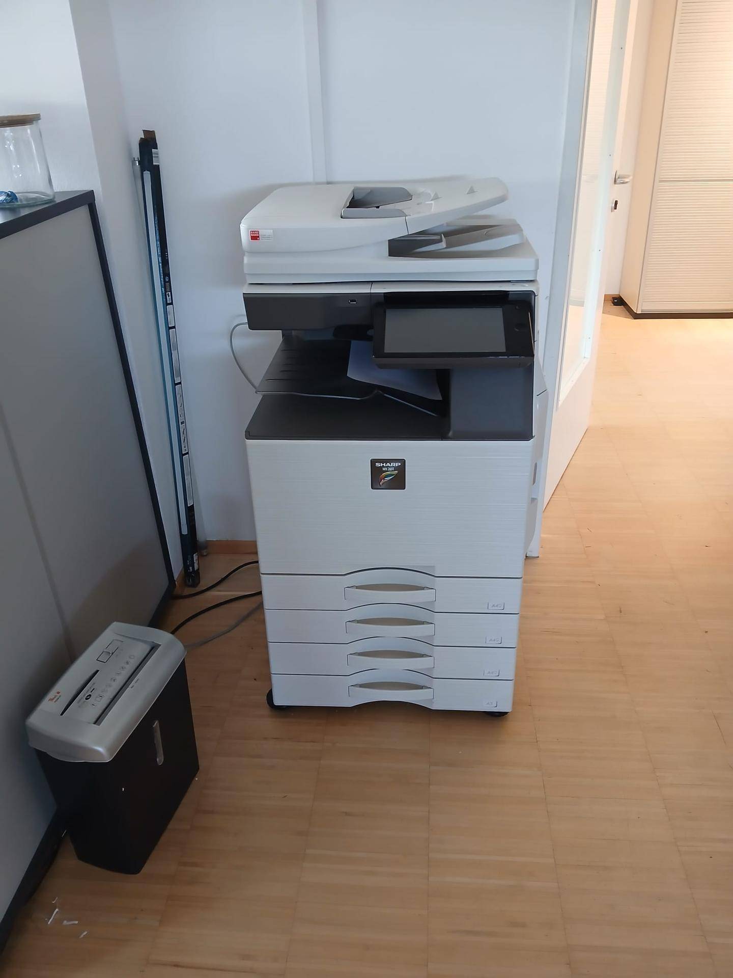 Großer Bürodrucker und Aktenvernichter auf einem Laminatboden in einem Bürobereich.